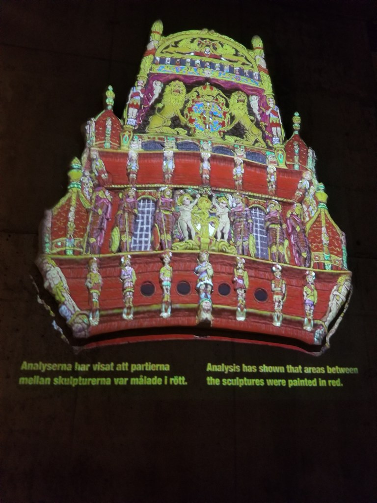 A photo of an illustration of the back of the ship the way it once looked like. It was quite colorful.