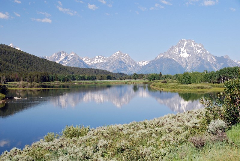 Grand Teton and a few other mountains in the Teton range reflected in a lake.