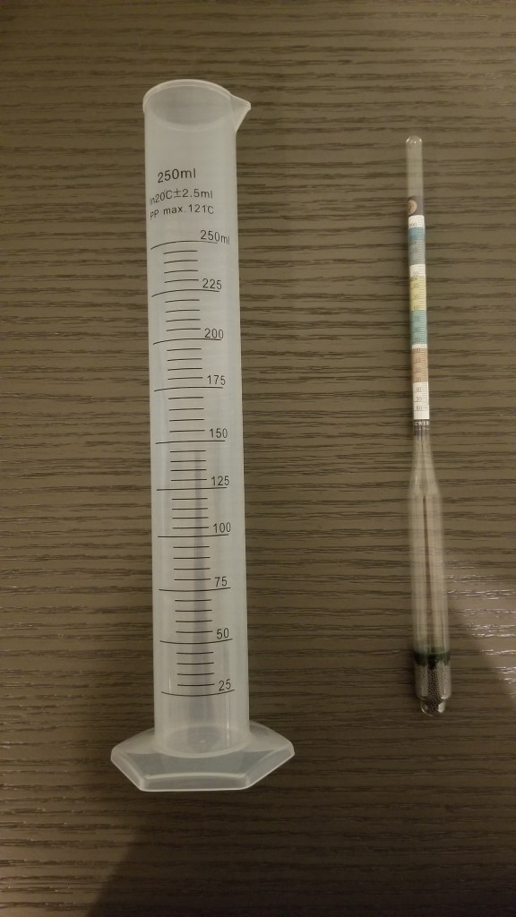 Long white plastic measuring cup with a hydrometer | Measuring Alcohol by Volume in Home Brews