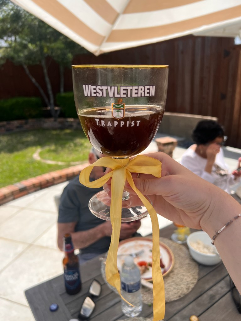 My daughter holding a Westvleteren 12 glass with a bow. Grandpa and grandma sitting on chairs in the background | The Great Sun and Moon Spectacle