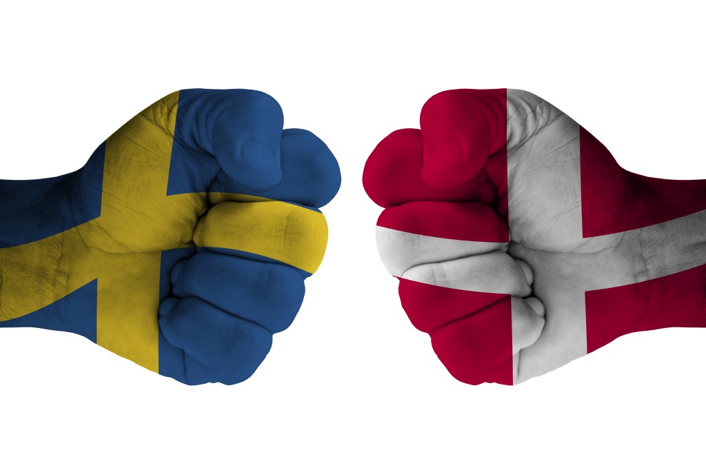 On the left, a fist with a yellow and blue flag. On the right, a fist with a red and white flag. 