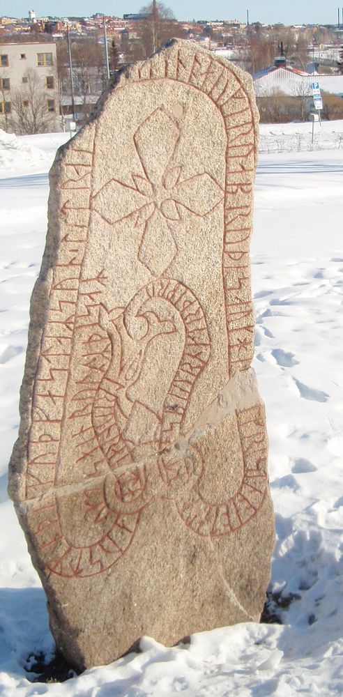 A runestone with runes and a picture of snake like creature.