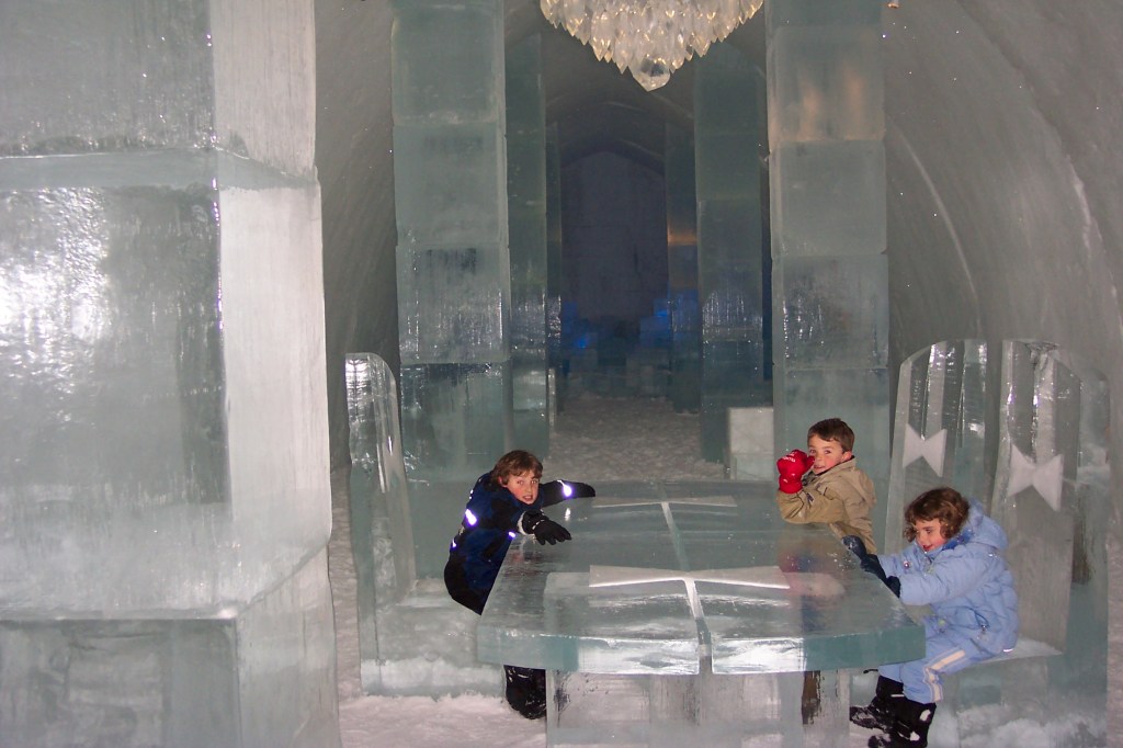 Photo is of a large ice table and ice chairs located in the middle of the lobby, which is filled with tall pillars made of ice at the ice hotel. Polar Nights Are Phenomenal and Cover a Large Area