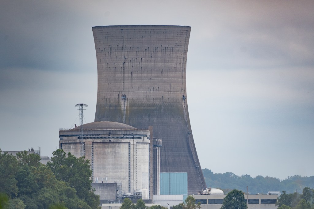 The photo is taken in 2024 and shows the Three Mile Island Nuclear Plant with a nuclear reactor building and the associated coolant tower.