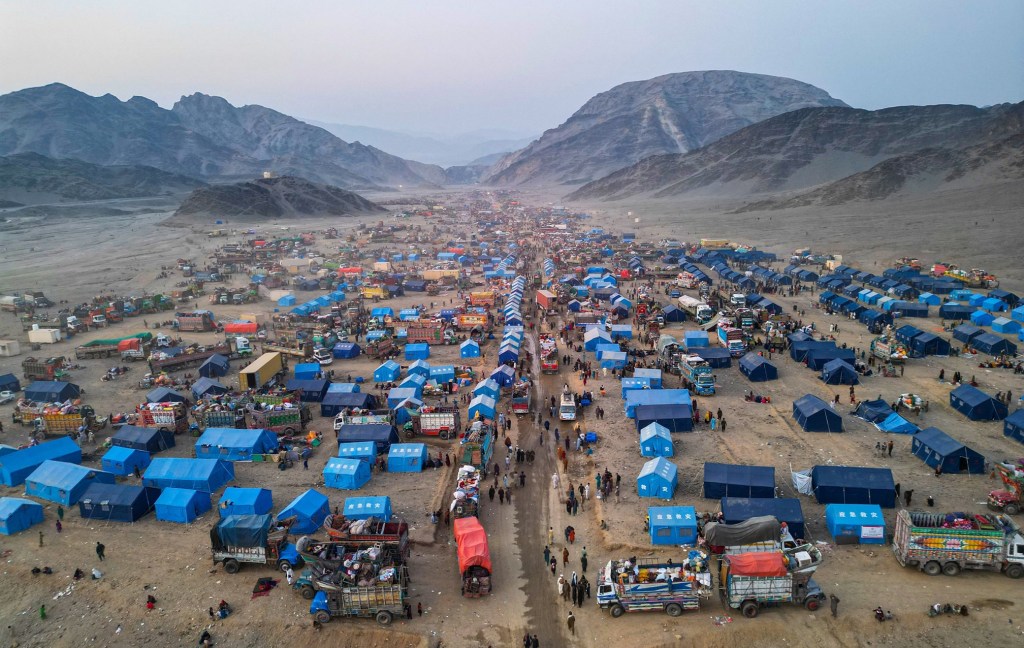 Aerial photo of thousands of mostly blue tents on a background of mountainous terrain. | There are more than 100 million forcibly displaced people