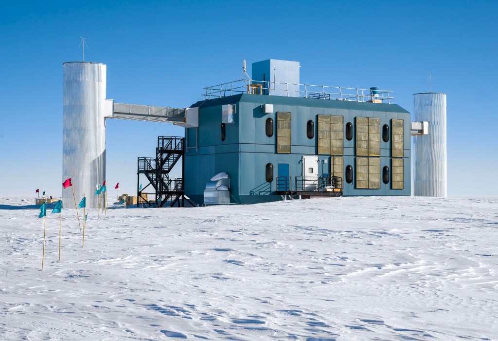 The photo shows a big blue building sitting on tip of white ice.